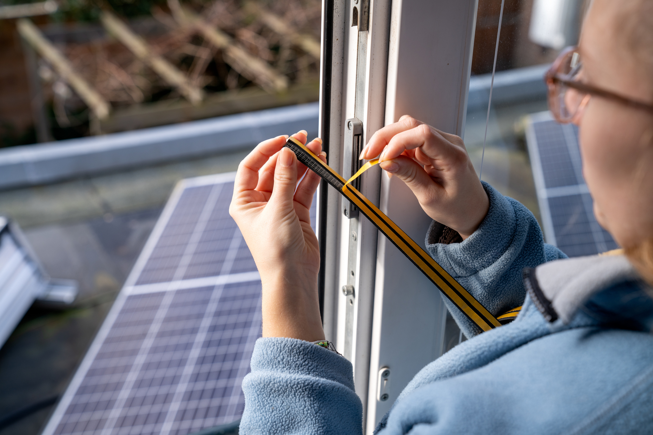 Young woman makes her home energy efficient with the help of draft strip.